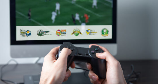 Man playing Football. Hands holding console controller in home