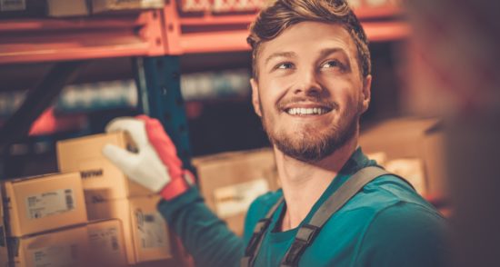 Man working in warehouse wearing gloves touching box